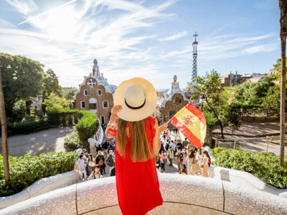 woman tourist red dress enjoying great view standing with spanish flag terrace famous guell park barcelona